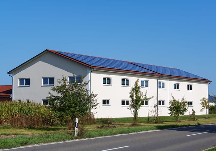 Workers installing solar panels on a large roof